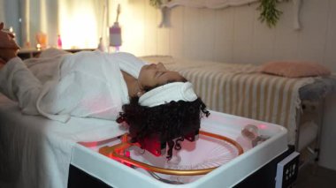 Bir güzellik kliniğinde basınçlı su kılı masajı yaptıran genç bir kadının yavaş çekim videosu.