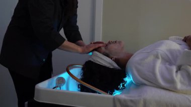 Profesyonel güzellik uzmanı tarafından güzellik kliniğinde genç bir kadına yapılan ağır çekimli yüz masajı.