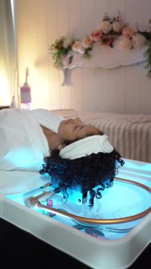 Bir güzellik kliniğinde basınçlı su kılı masajı yapan genç bir kadının yavaş çekim videosu.