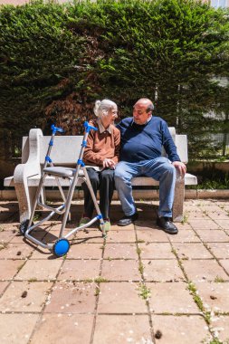 Aile babası ve geçici bir kadın huzur içinde bir huzurevinin bahçesindeki bankta oturuyorlar.