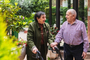 Mutlu yaşlı çift aylakları kullanıyor ve bir huzurevinin bahçesinde sohbet ediyor, dışarıda birlikte vakit geçiriyorlar.