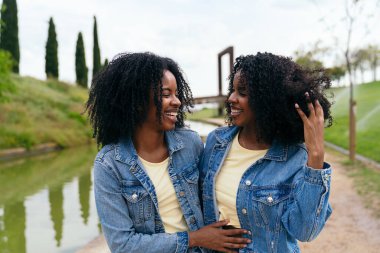 Afrikalı iki mutlu ikiz kardeş güzel bir park ortamında gülüp eğleniyorlar.