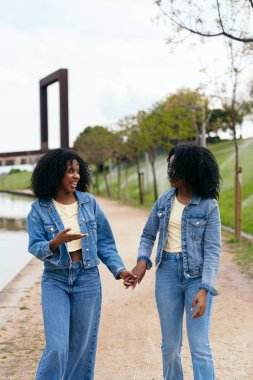 Afrika 'da kot ceket giyen iki mutlu ikiz kardeş el ele tutuşup parkta birlikte yürüyüp eğleniyorlar.