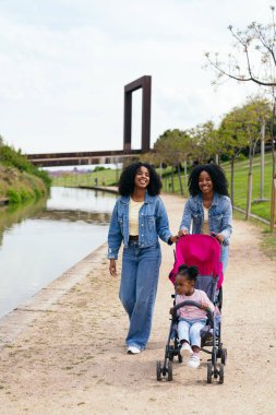 İkiz kardeşler parkta yürümekten zevk alıyorlar. Yeğenlerini bebek arabasıyla kanalda gezdiriyorlar. Yürek ısıtan bir aile sahnesi yaratıyorlar.