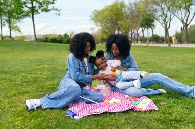 İki ikiz kız kardeş parkta yeğenleriyle eğlenceli bir piknik yapıyorlar. Sevimli aile anıları yaratıyorlar.