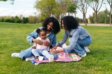 İki ikiz kardeş parkta yeğenleriyle eğlenceli bir pikniğin tadını çıkarıyor, kahkahalarını paylaşıyor ve güzel aile anıları yaratıyorlar.