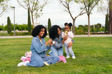 İki ikiz kardeş parkta yeğenleriyle piknik yapıyor, atıştırmalıkların tadını çıkarıyor ve mutlu anılar yaratıyorlar.