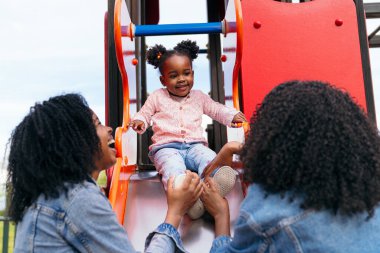İkiz anneler kızlarını parkta güneşli bir günün tadını çıkarırken oyun parkının dibinde yakalıyorlar.
