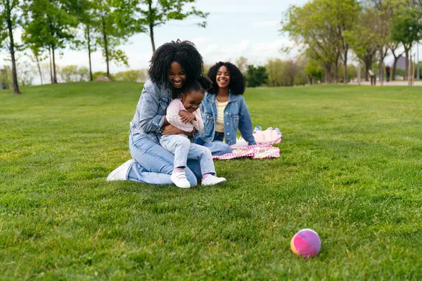 Anne ve kızı parkta pikniğin tadını çıkarıyorlar. Birlikte gülüp kucaklaşıyorlar. Yürek ısıtan bir aile anı yaratıyorlar.