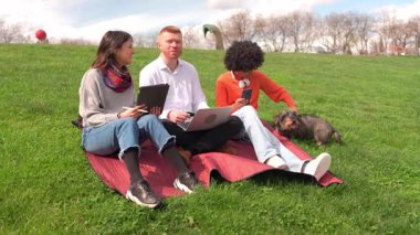 Dışarıda elektronik cihazlarla çalışan öğrenciler, yavaş çekimde köpekleriyle vakit geçiriyorlar.