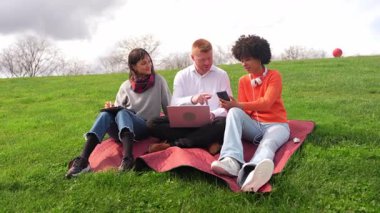 Öğrenciler dizüstü bilgisayar ve akıllı telefon kullanıyor. Birlikte parkta vakit geçiriyorlar. Yavaş çekim montajı.