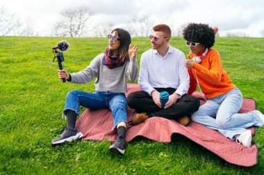 Parkta güneşli bir günün tadını çıkarırken, üç içerikli yaratıcı açık havada canlı bir video blogu çekiyor.