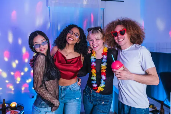 Dört neşeli çoklu etnik arkadaş renkli disko ışıklarıyla eğleniyor, sarılıyor ve gülümsüyor.