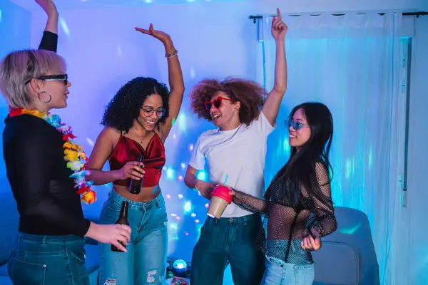 Bir grup neşeli çoklu etnik arkadaş renkli disko ışıkları altında dans edip içiyorlar.