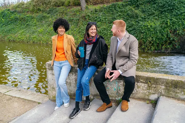 Üç meslektaş alçak bir duvarda oturmuş sohbet ve kahkahalarla vakit geçiriyorlar.