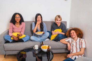 Çok ırklı dört genç arkadaş evlerindeki bir kanepede oturup atıştırmalık ve içeceklerle film gecesi yapıyorlar.