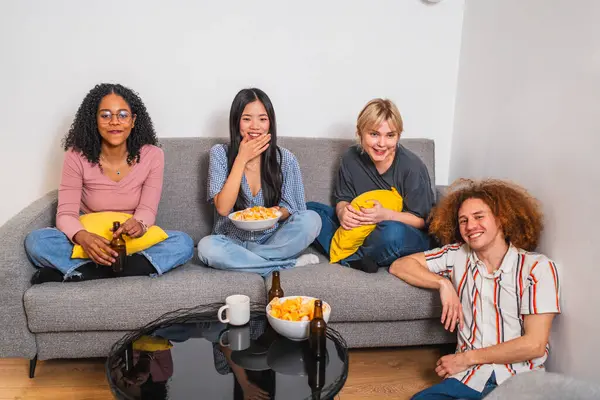 Çok ırklı dört genç arkadaş evlerindeki bir kanepede oturup atıştırmalık ve içeceklerle film gecesi yapıyorlar.