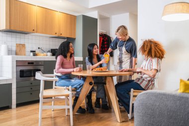 Modern bir dairede yuvarlak bir masada oturan dört genç arkadaş kahvaltı ve sohbetin tadını çıkarıyorlar.