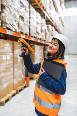 Depo çalışanı paketleri barkod okuyucu kullanarak tarıyor, dağıtım merkezinde envanter ve lojistik yönetiyor.