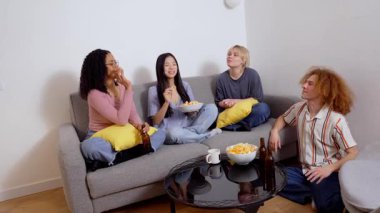 Dört farklı arkadaş rahat bir kanepede oturup atıştırmalıkları, içecekleri, kahkahaları ve animasyonlu sohbetleri ağır çekimde paylaşıyorlar.