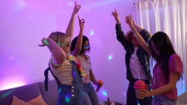 Ev ortamında renkli disko ışıklarıyla aydınlatılan ve ağır çekimde karaoke yapıp dans eden dört çok ırklı bayan arkadaş.