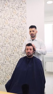 Ağır çekim klinik ortamında ileri saç yenileme prosedürü için hazırlık konsültasyonu sırasında hastanın kafa derisini dikkatlice inceleyen tıbbi uzman.