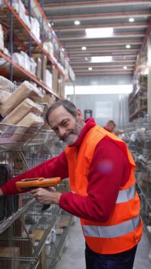 Barkod tarayıcı kullanarak ambarda veya depoda gülümseyen ve tarayan üst düzey erkek işçiler.