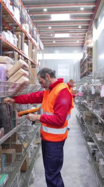 Modern lojistik dağıtım merkezinde rafları düzenlerken barkod okuyucu kullanarak envanter paketlerini tarayan profesyonel bir depo çalışanı.