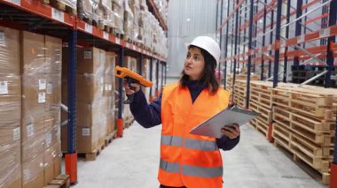 Depo çalışanı paketleri tarıyor ve envanteri barkod tarayıcı ve pano ile kontrol ediyor.