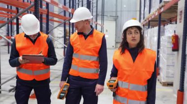 Büyük depoda çalışan lojistik işçileri, envanter için barkod tarayıcıları ve panoları kullanıyorlar.