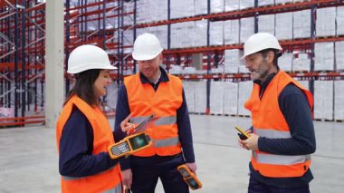 Depo üyeleri el bilgisayarı kullanarak işbirliği yapıyor, geniş, organize depolama tesisinde lojistiği verimli bir şekilde yönetiyorlar.