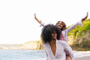 Genç, çok ırklı bir çift kumsalda eğleniyor, yaz tatilinin tadını çıkarıyor.