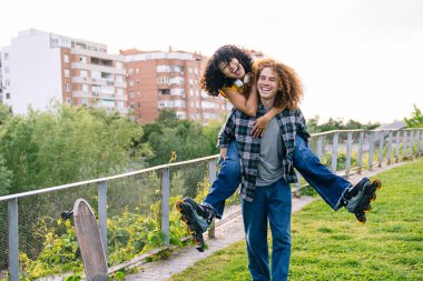 Mutlu çift şehir parkında paten kayarken eğleniyor, eğlenceli bir öğleden sonranın tadını çıkarıyor.