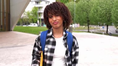 Kampüste duran kendinden emin Afro-Amerikan üniversite öğrencisi akademik başarıyı ve kişisel gelişimi parlak bir gülümseme ve umut dolu bir ifadeyle yayıyor.