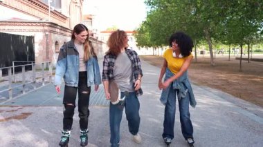 Mutlu arkadaşlar şehir parkında yavaş çekim montajıyla kayarak gezintiden zevk alıyorlar.