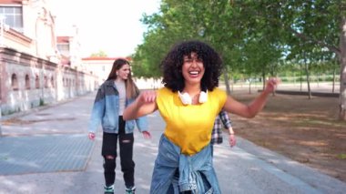 Mutlu genç bir kadın arkadaşlarıyla gezmekten zevk alıyor, kulaklıkları boynunda, gülümsüyor ve gülüyor.