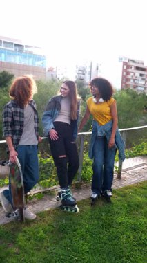 Bir grup neşeli genç arkadaş birlikte vakit geçiriyorlar, sohbet ediyorlar ve kaykaylarla poz veriyorlar ve yavaş çekimde patenlerle oynuyorlar.