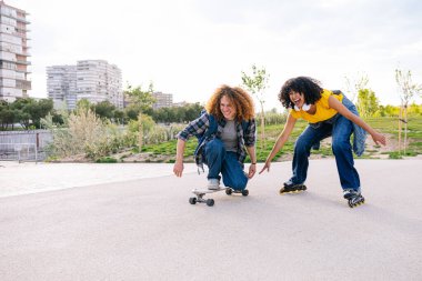 Öğrenciler parkta birlikte kaykay yapıyor, gülüyor ve boş zamanlarının tadını çıkarıyorlar.