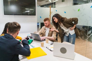 İş adamları, bir dizüstü bilgisayardaki pazarlama verilerini analiz ediyor, stratejileri tartışıyor ve modern bir iş yerinde işbirliği yapıyorlar.