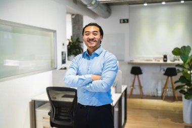 Gülümseyen Asyalı bir müdürün portresi modern bir çalışma ofisinde kollarını kavuşturarak durarak profesyonellik ve pozitiflik yayıyor.