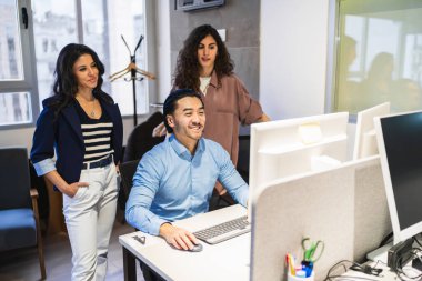 Projelerinde yaratıcılığı ve yeniliği teşvik eden, parlak ve modern bir çalışma alanında bir bilgisayar üzerinde işbirliği yapan iş ekibi. Biri Çince.