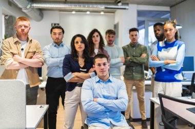 Çağdaş bir ofis ortamında takım çalışması ve güven sergileyen kolları çapraz duran çeşitli profesyonel gruplar