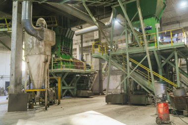 Bir ahşap işleme fabrikasında, büyük bir endüstriyel odun öğütücü keresteyi talaş, odun parçası ve ağaç kabuğuna dönüştürür ve üretim sürecini ön plana çıkarır.