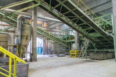 Taşıyıcı bantlar kereste tozu, talaş ve kereste kabuğu taşıyarak bir kereste işleme tesisinde endüstriyel üretim hattını vurguluyor.