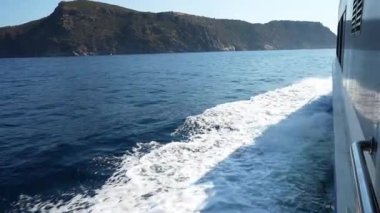 Beyaz yelkenli teknesi, güllerin, girona 'nın, İspanya' nın kıyı manzarasının yakınındaki pırıl pırıl Akdeniz sularını keserek güneşli mavi gökyüzünün altında manzaralı deniz manzarası yaratıyor.