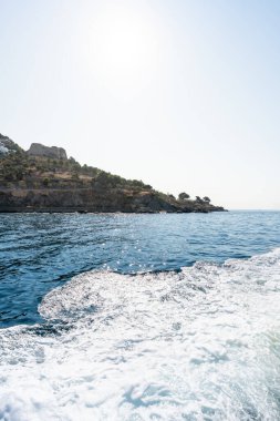 Beyaz dalgalar güllerin, İspanya 'nın kayalık kıyı şeridine çarpıyor, parlak yaz güneşinin altında, pitoresk bir deniz manzarası yaratıyor
