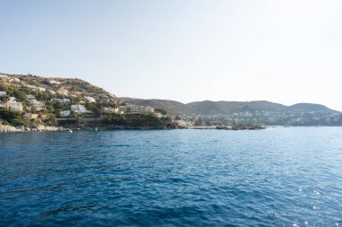 Sakin mavi Akdeniz kıyısı kayalık kıyı şeridi ile beyaz evler ve oteller açık gökyüzü altında güller, girona