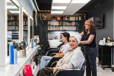 Müşteriler saç yıkama ve stil hizmetlerini seviyor. Modern bir kuaför salonunda yeni bir görünüme hazırlanıyorlar.