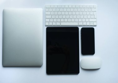 Beyaz arka planda modern beyaz tablet, akıllı telefon, klavye ve dizüstü bilgisayar