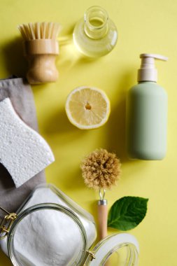 Çevre temizliği. Temizlik için çevre dostu şeyler. Çevre temizleme şirketi. Tahta fırça, limon, kabartma tozu, sarı arka planda sirke..